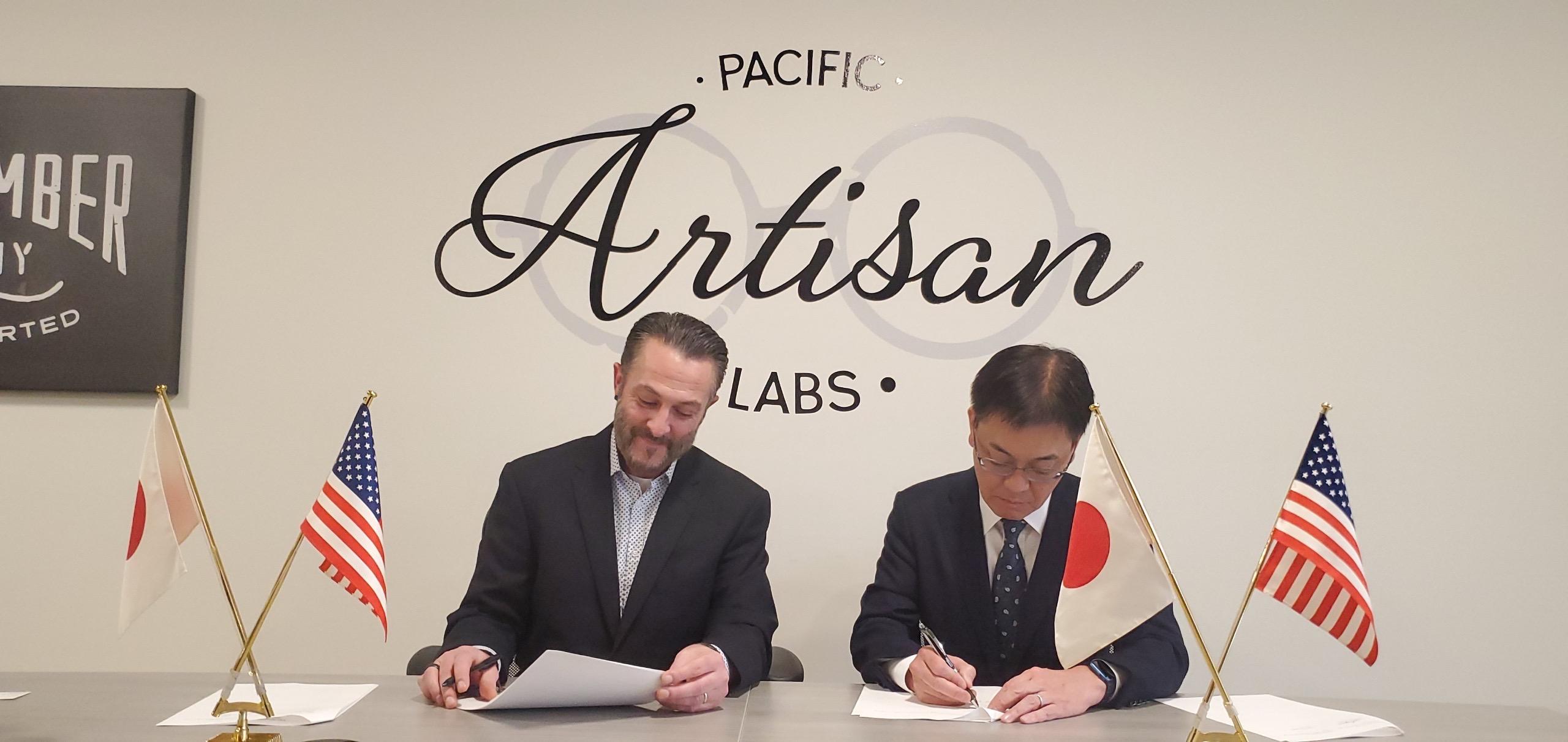 Brandon Butler and a Tokai Optical representative signing partnership documents